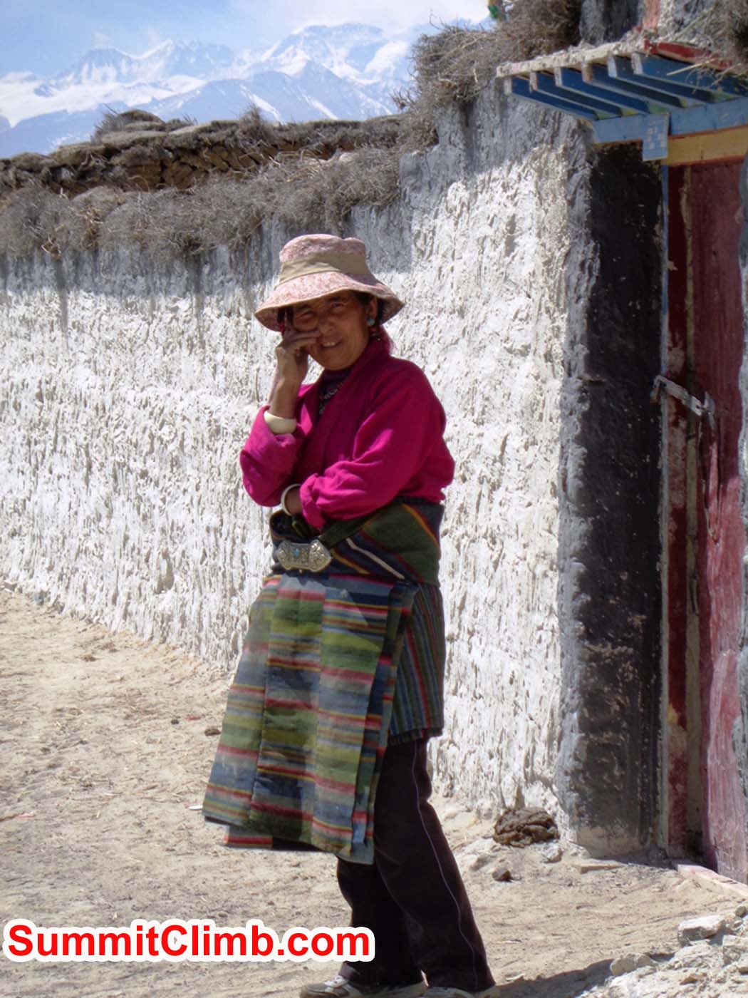 Tibetan plateau woman stands outside her house with Mount Cho Oyu and Everest in the background. Sacha Guittet photo
