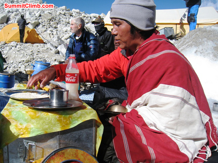 Lama Tashi scoops up a handfull of rice to toss onto the basecamp alter during the blessing ceremony. Scott Smith Photo.