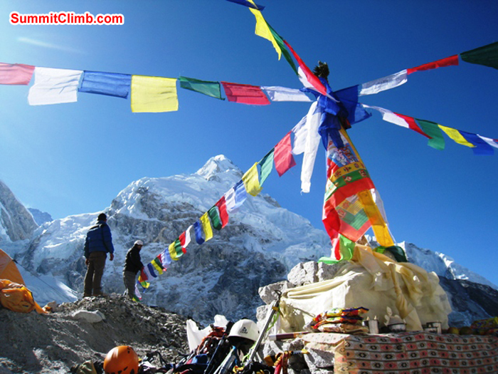 Sherpas putting up prayer flags in basecamp. Summits of Lhotse and Nuptse in background. Scott Smith Photo.