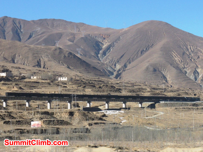 Freight train whisks along  an elevated concrete railway  traversing the plateau from Lhasa to Shigatse.