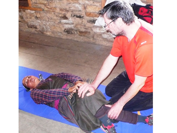 Wolfgang Nicola,  physiotherapist from Germany, shows Puti Sherpa how to stretch her sore back. Villagers work hard and develop physical problems which can be helped sustainably by stretching and massage.