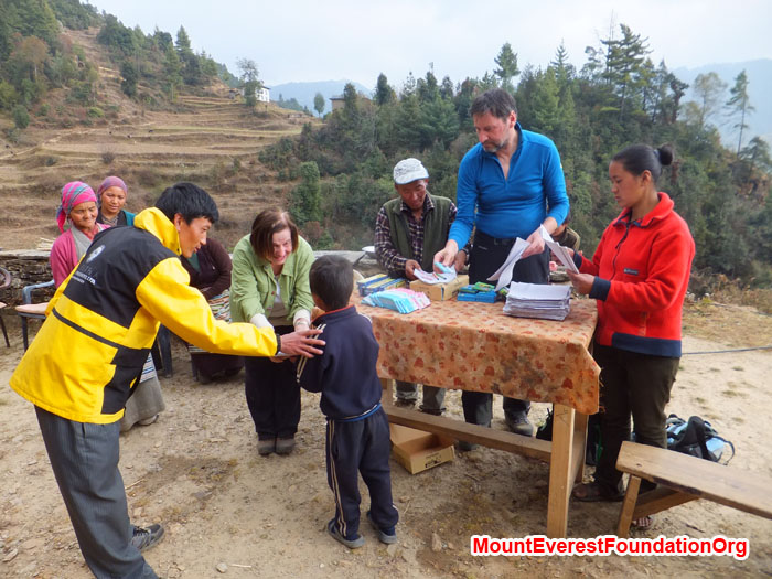 Teacher Jamyang, Anne Kates, Jangbu Sherpa, Wolfgang Nicola and Yangjie Sherpa distribute books, paper, and pens to a local student in Dhorkharka village. Photo by Dan Mazur